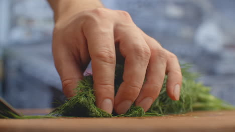 Closeup-of-cutting-green-dill-on-a-board-in-the-kitchen-on-a-wooden-board.-cutting-grass-and-greenery